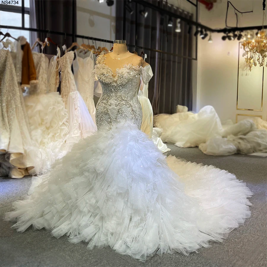 Front-facing shot of the luxury African mermaid wedding dress on a mannequin, highlighting the detailed hand-beaded bodice and sweeping ruffled train.