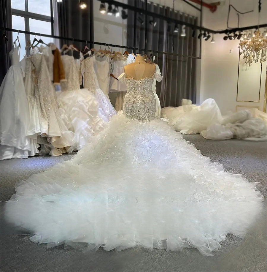 Another rear view of the elegant beaded bridal gown on a mannequin, emphasizing the dramatic volume and texture of the long ruffled train.