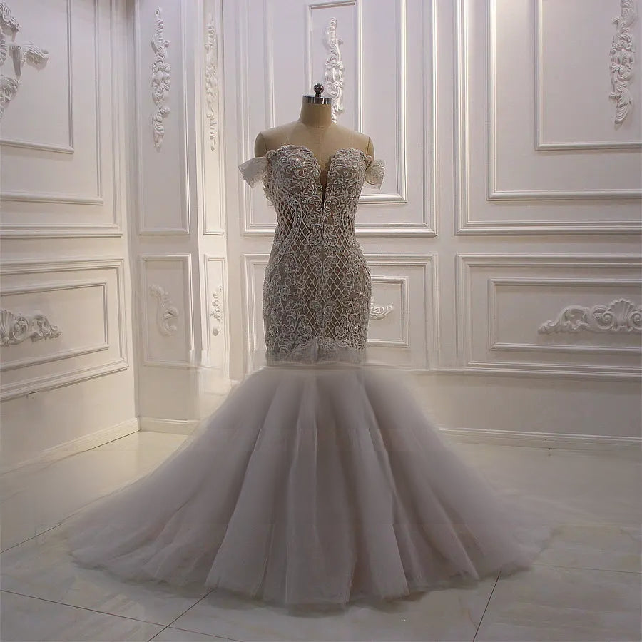 Full-length view of the African off-shoulder mermaid wedding dress featuring an elegantly fitted lace bodice and a dramatic flared tulle skirt on a mannequin.