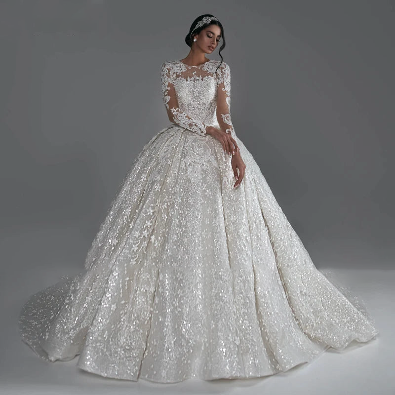 Elegant ball gown wedding dress with long sleeves, featuring extensive luxury beading, intricate lace details, and a grand court train.