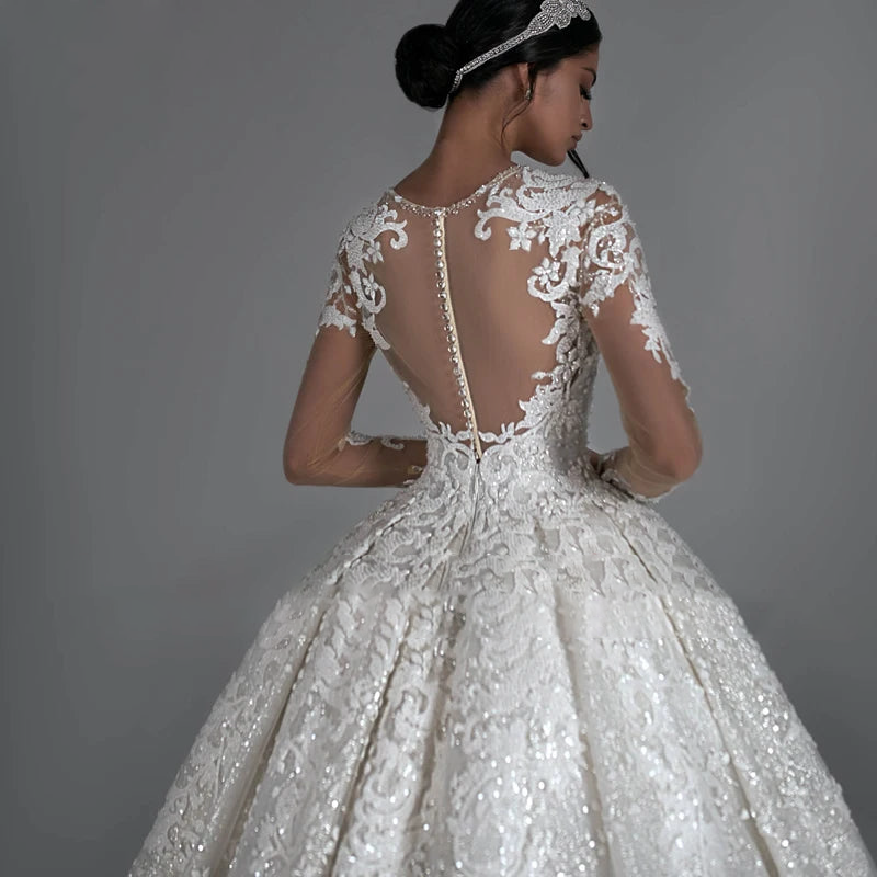 A beautiful bride showcasing the sheer, beaded lace back of this ball gown, complete with delicate button-down detailing and a dramatic court train.