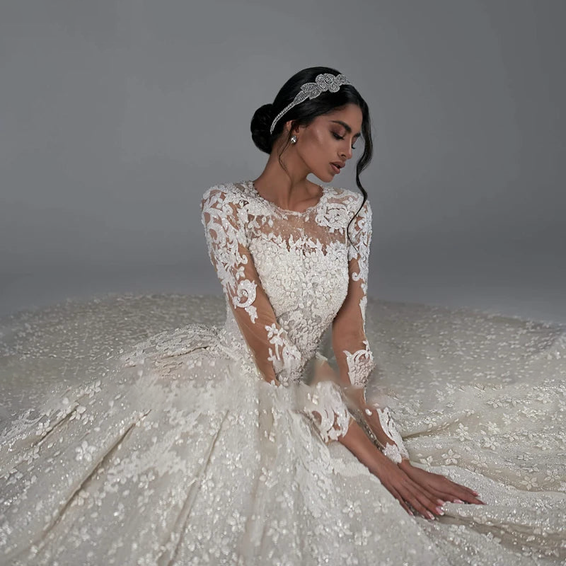 A seated bride elegantly displaying the voluminous skirt and beaded lace bodice of this classic AmyLvager bridal gown.