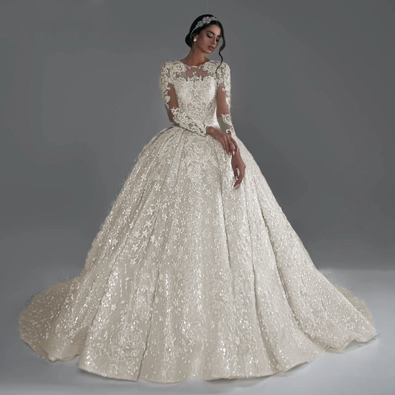 A bride sitting on the floor in the classic ball gown, with her beaded lace skirt spread out to showcase its intricate design.