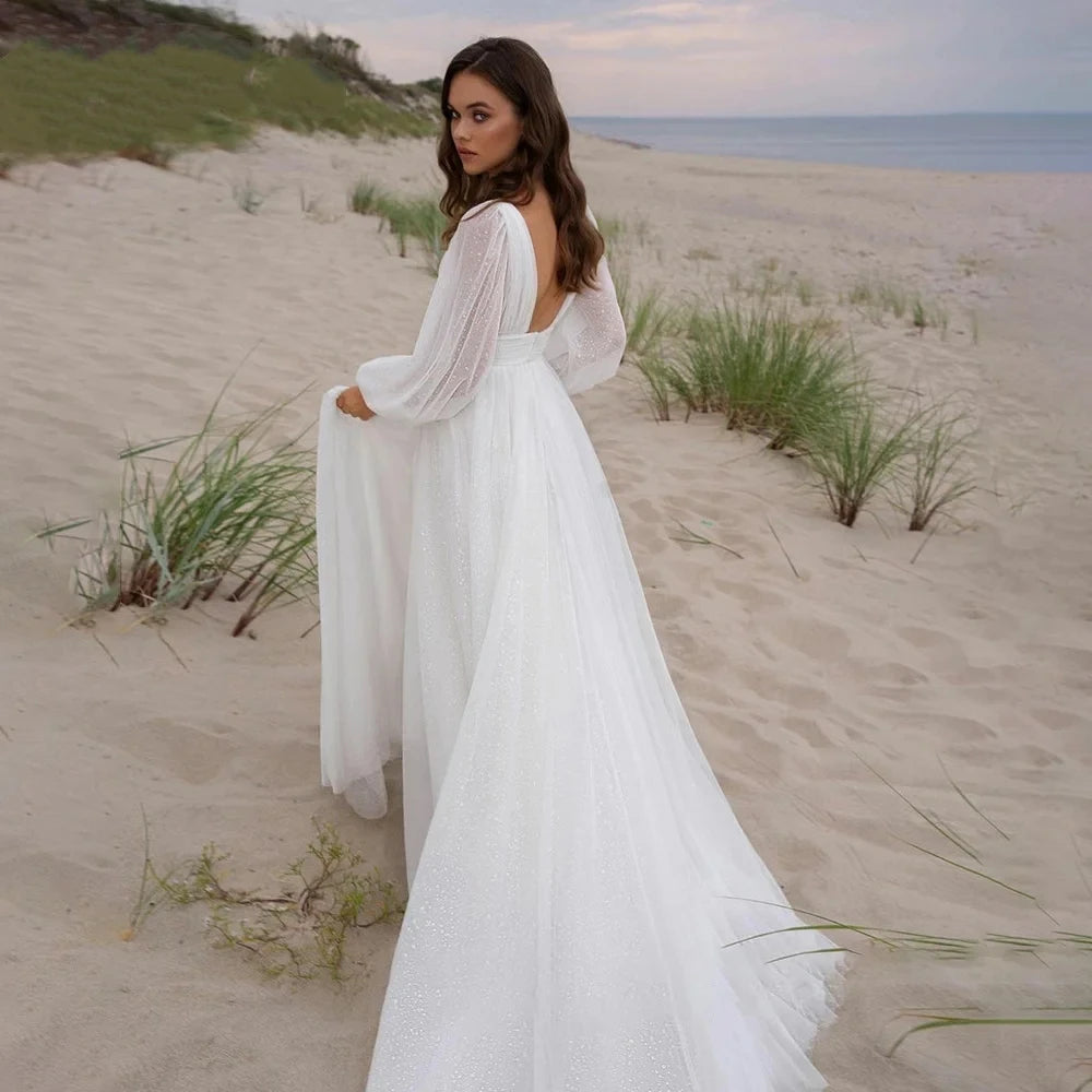 Back view of a simple BOHO bridal gown with long sheer puff sleeves and a flowing tulle train, perfect for a vintage-inspired beach wedding.