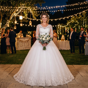 Full-length front view of a model wearing a vintage ball gown wedding dress featuring a plunging V-neckline, elegant long sheer lace sleeves, and a majestic layered tulle skirt.