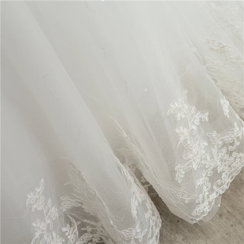 Detailed macro view of the sheer illusion mesh long sleeve, showcasing the premium floral lace appliqués running down the arm to the wrist cuffs of the vintage bridal gown.
