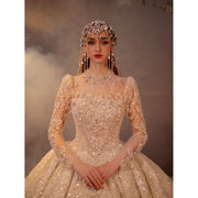 Close-up of a 2025 luxury ball gown wedding dress with a square neckline and long illusion sleeves, featuring heavy crystal beading and a matching royal jeweled headpiece.