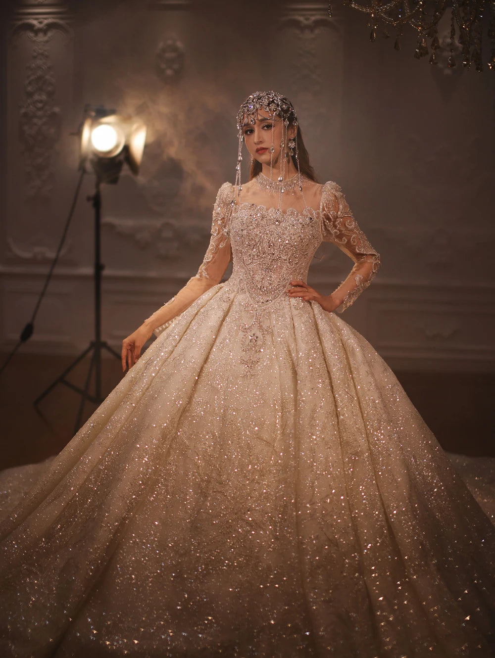 Full frontal pose of a bride in a sparkling long-sleeve ball gown, highlighting the voluminous shimmering skirt and intricate bodice detailing for a royal bridal look.
