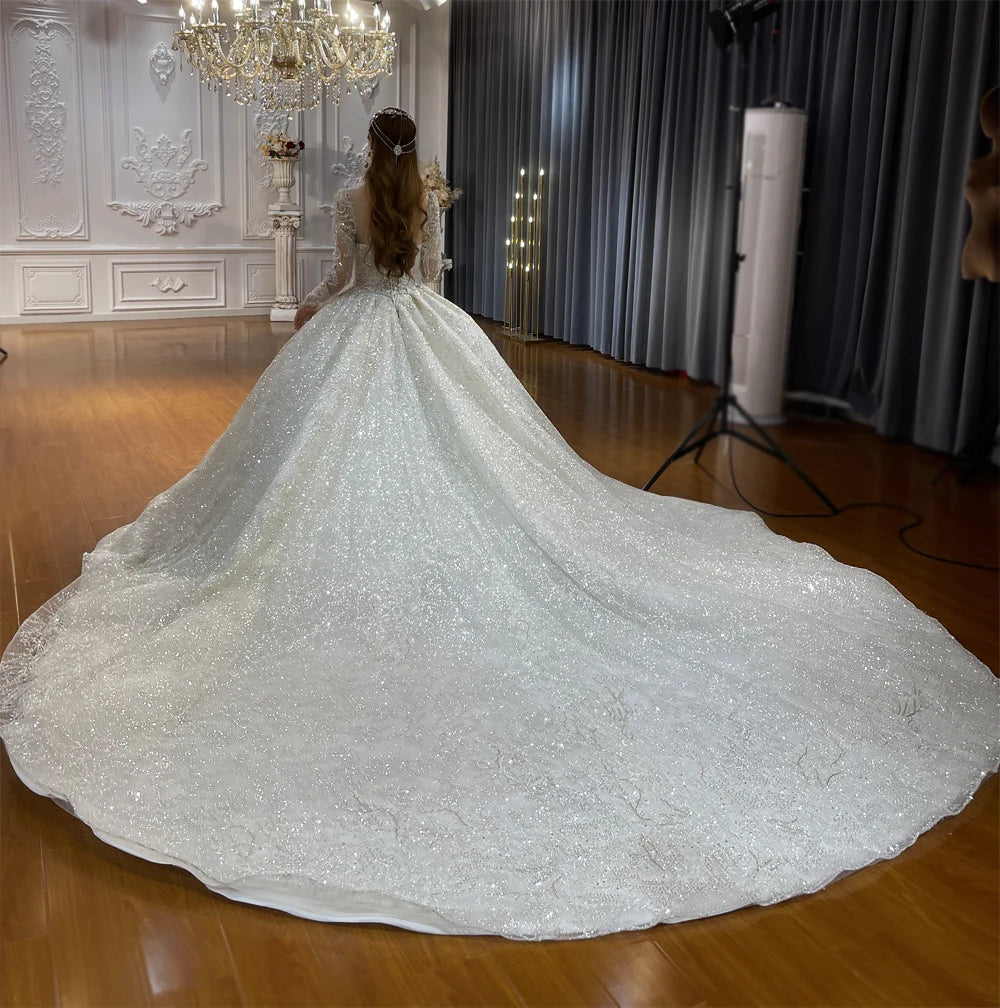 Rear view of a luxury bridal ball gown showcasing a grand cathedral-length shimmering train and delicate lace-trimmed back with elegant detailing.