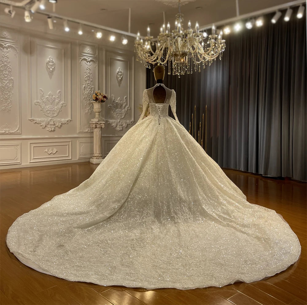 Back view of a luxury ball gown wedding dress on a mannequin, featuring an open back with a lace-up corset and a massive, sparkling circular cathedral train.