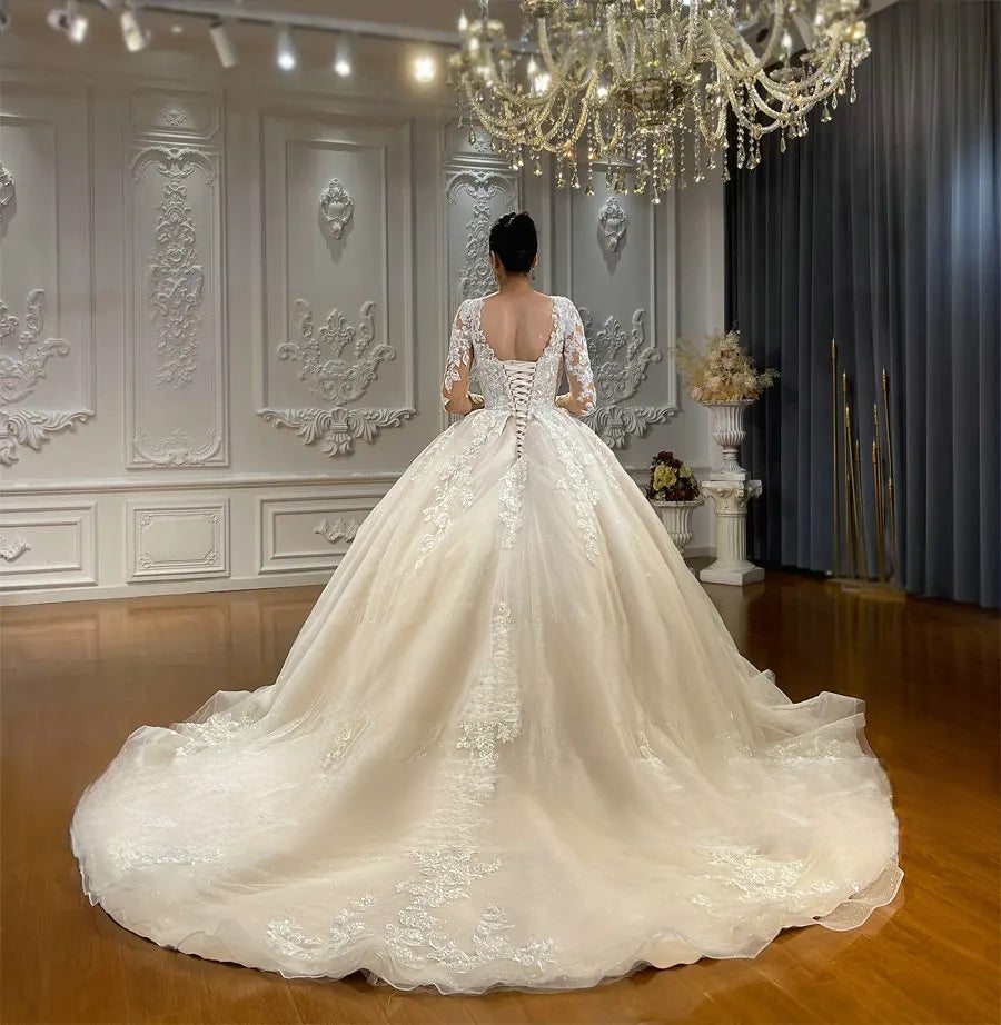Rear view of a luxury wedding dress highlighting a classic lace-up corset back design and a magnificent, sweeping cathedral-length train with delicate floral lace embroidery.