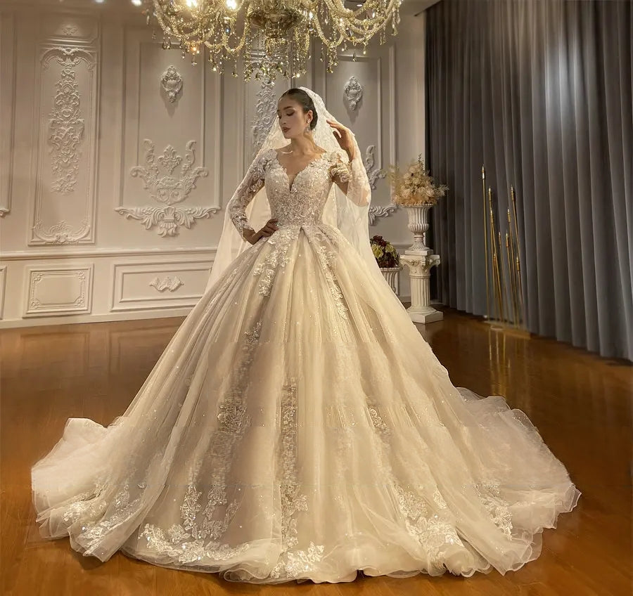 Elegant beach style A-line bridal gown with long sleeves and a full ballroom skirt displayed on a hanger, showcasing the intricate lace hemline and shimmering fabric texture.