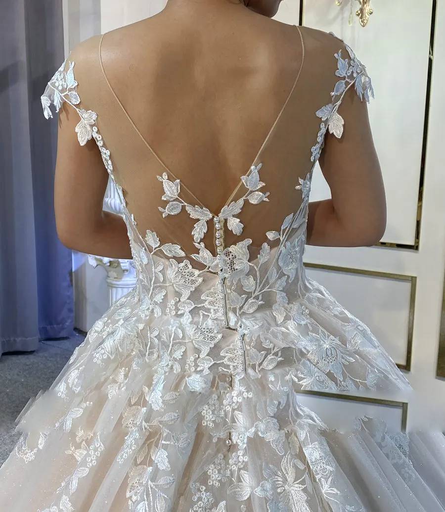 Detailed back view of a beach wedding dress featuring a low illusion V-back, dainty pearl buttons, and vine-inspired lace patterns.