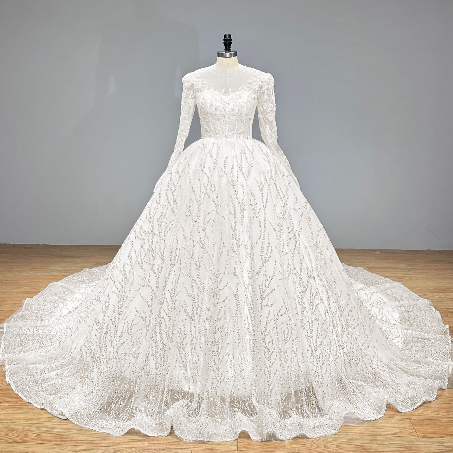 Front studio view of a premium white long sleeve beaded ball gown wedding dress with an expansive branch-patterned sequined skirt.