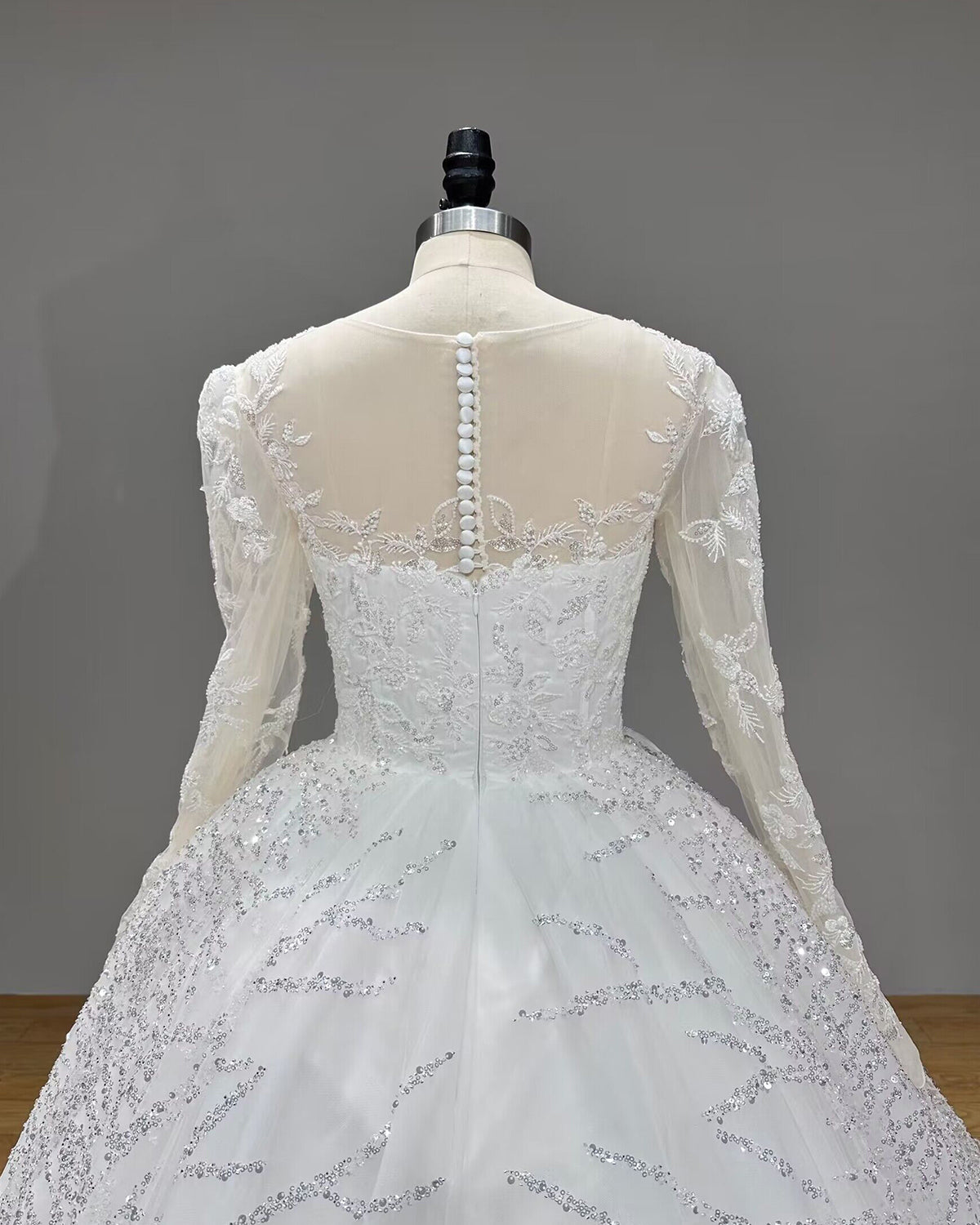 Detailed back view of an illusion see-through back wedding dress featuring a row of elegant white buttons over a sheer mesh lace bodice.