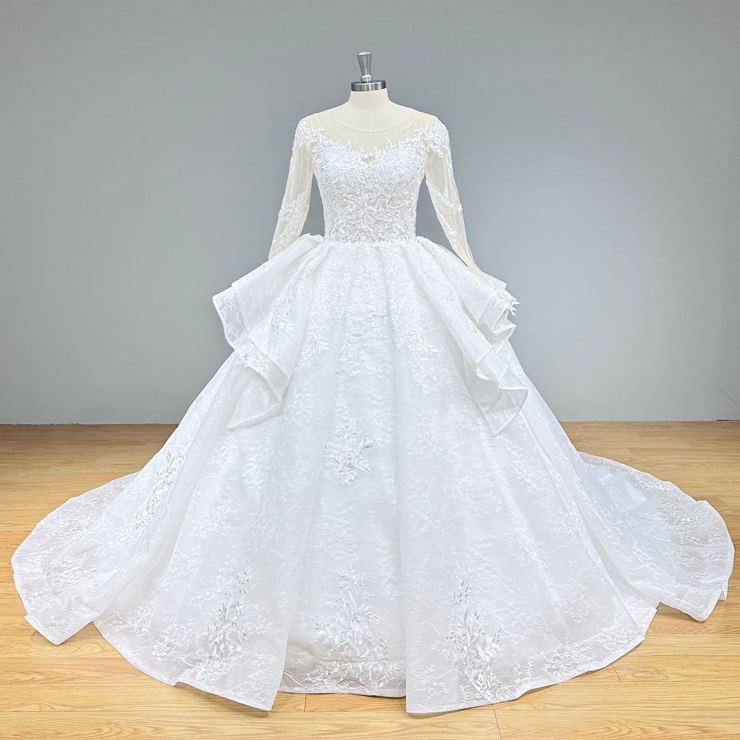 Detailed front view of a luxury vintage ball gown wedding dress emphasizing the structured basque waistline and layered organza peplum ruffles.
