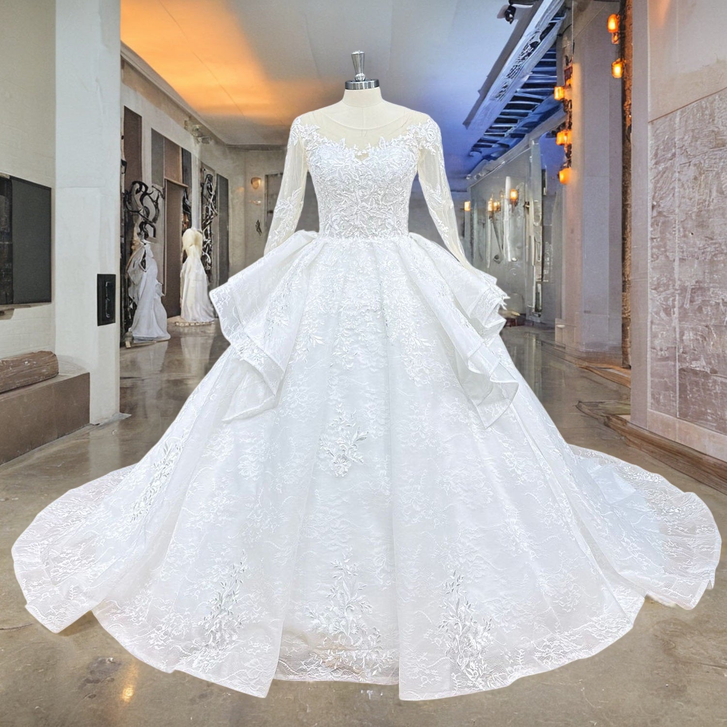 Vintage-style long-sleeve white ball gown wedding dress with an illusion neckline and layered pick-up skirt displayed on a mannequin.