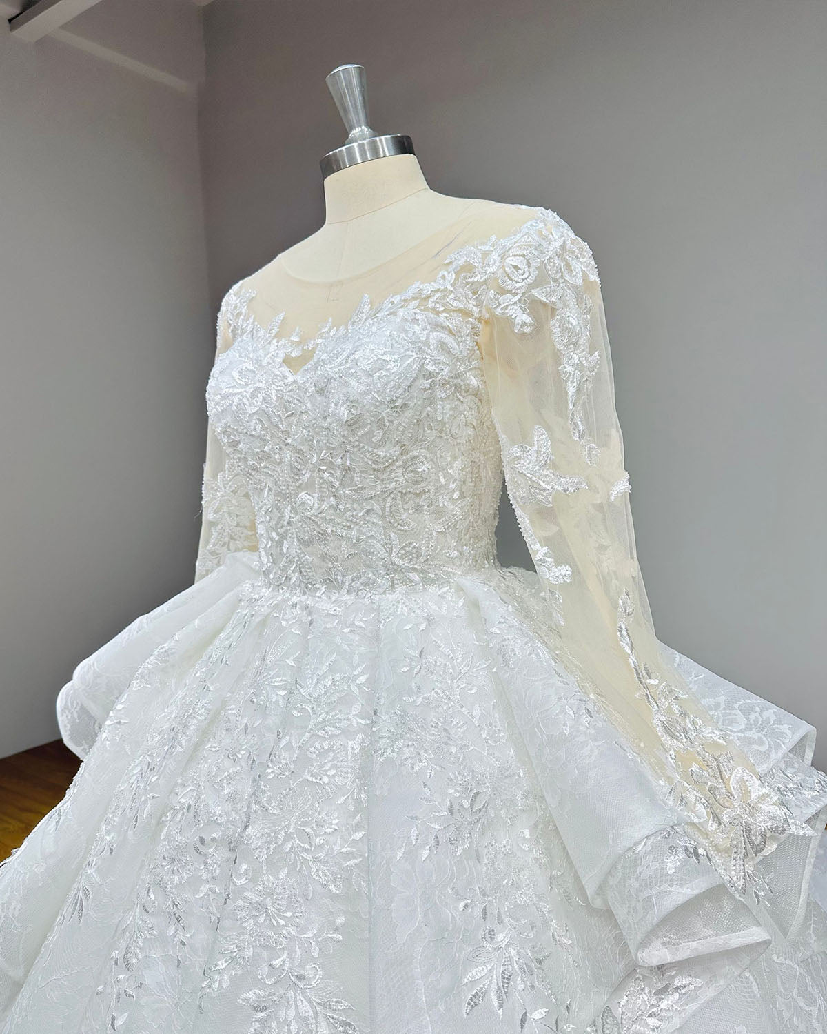 Side angle close-up of a long-sleeve bridal gown showcasing the texture of the beaded floral embroidery on the bodice and sheer tulle sleeves.
