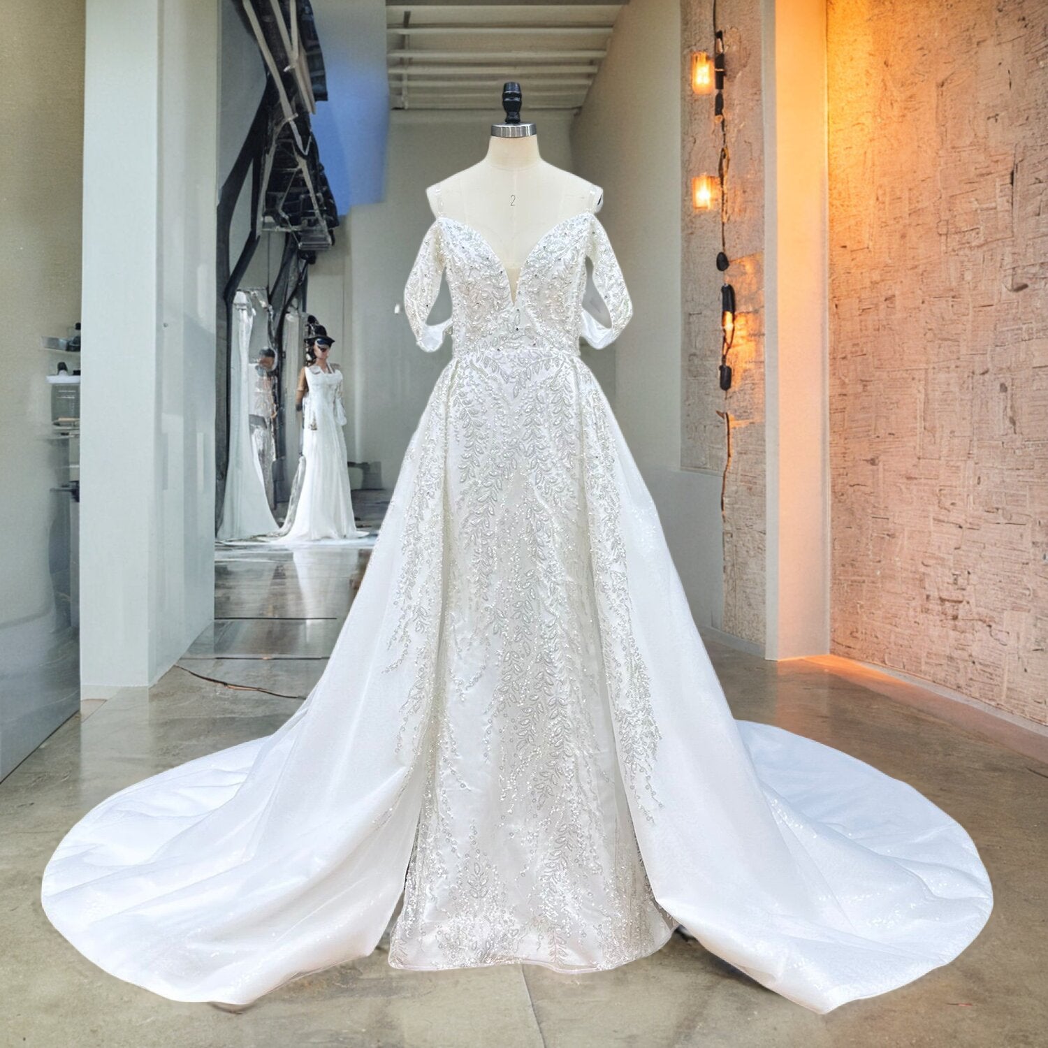 Full front view of a beaded lace mermaid wedding dress on a mannequin in a studio hallway, highlighting the fitted silhouette and the added volume of the detachable train.