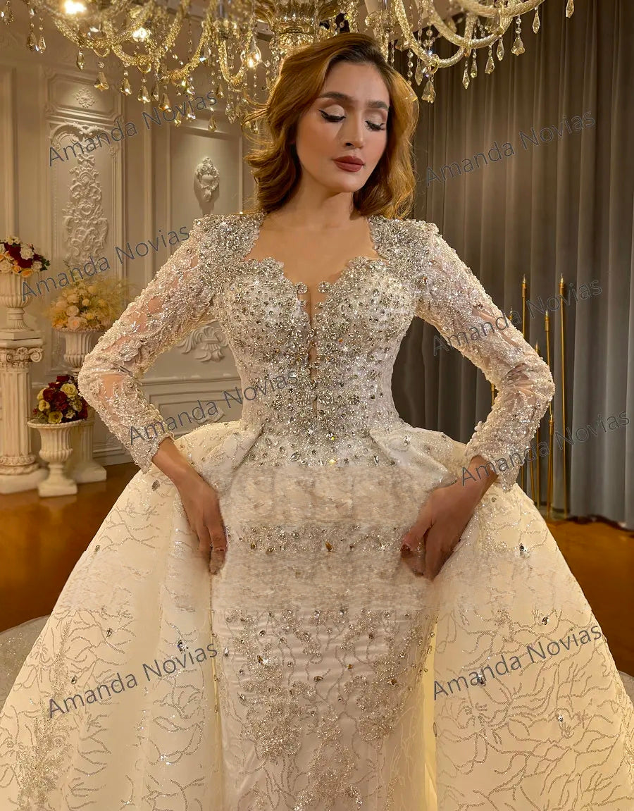 Detailed close-up of a luxury beaded bridal bodice, showcasing the exquisite handcrafted crystal rhinestones, silver embroidery, and sheer lace sleeves.