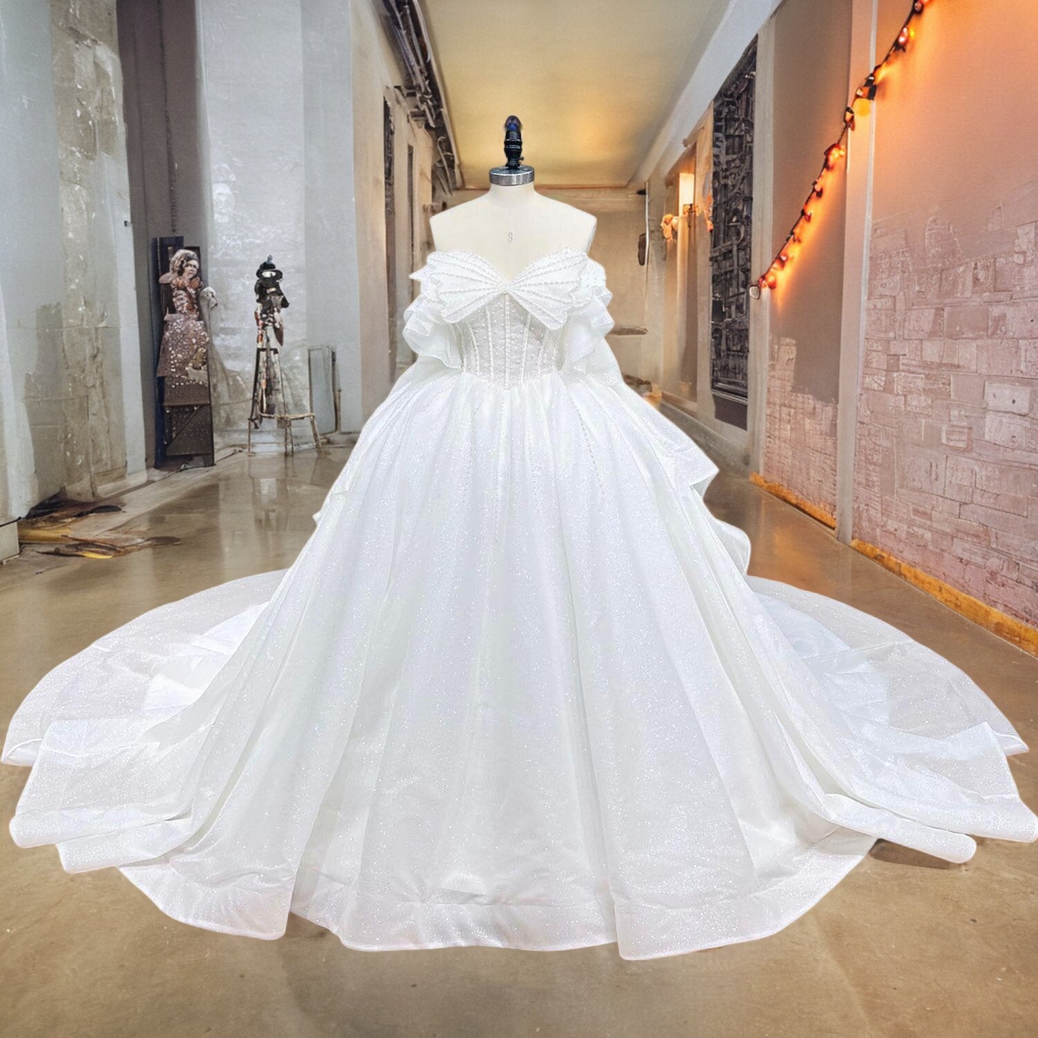 Premium shimmer satin and tulle wedding dress featuring a heavily embellished pearl bodice and a dramatic pleated overskirt silhouette, displayed on a mannequin in a showroom.