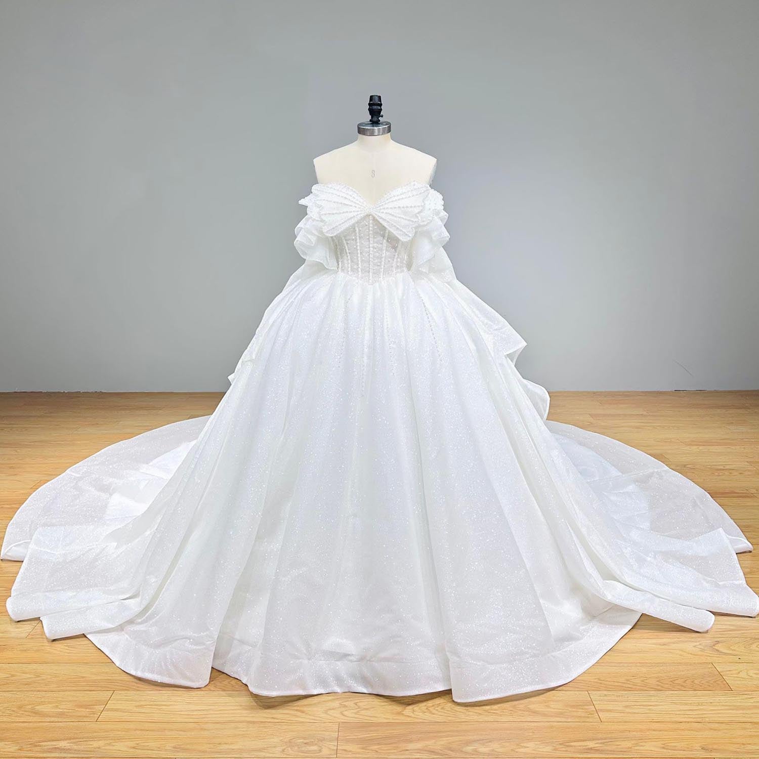 Front view of a white fairytale princess bridal gown on a dress form, displaying a signature butterfly-shaped bow accent across the sweetheart bustline.
