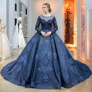Elegant model posing in a black ball gown wedding dress with long sheer sleeves and ornate lace appliques in a luxury bridal studio.
