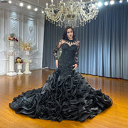 Elegant long-sleeved black mermaid wedding dress featuring an intricately beaded fitted bodice and a dramatic, voluminous ruffled flared skirt displayed in a luxury bridal showroom.