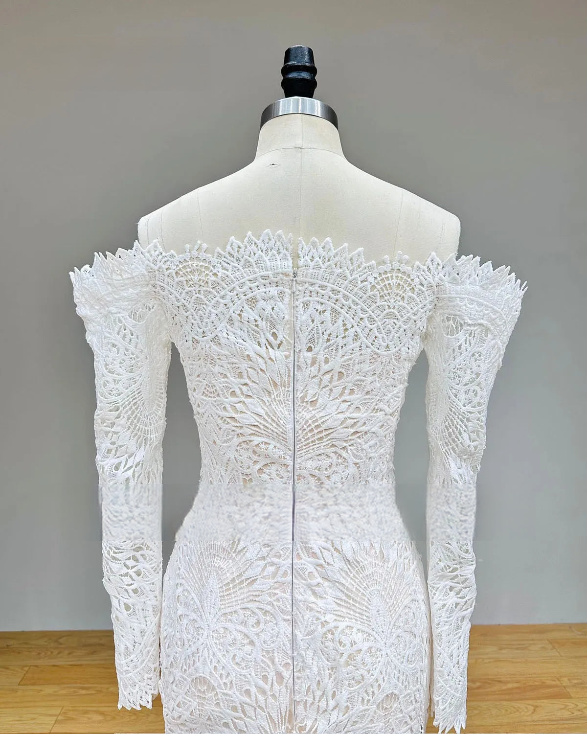 Detailed rear view of the lace wedding dress with zipper back, highlighting the off-the-shoulder long sleeves and intricate mandala-style lace patterns.