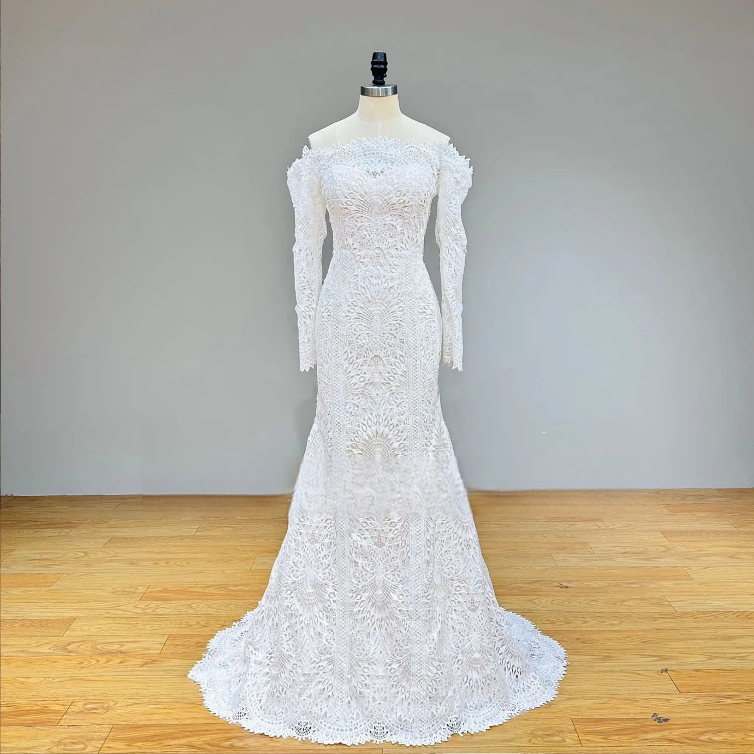 Full-length front perspective of a white lace mermaid bridal gown on a mannequin, showcasing the long sleeves, boat neckline, and floor-length fit-and-flare silhouette.