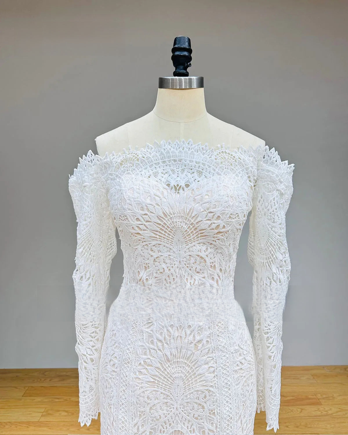 Close-up detail of the lace bodice and off-the-shoulder long sleeves of a mermaid wedding dress, featuring high-quality geometric and floral embroidery.
