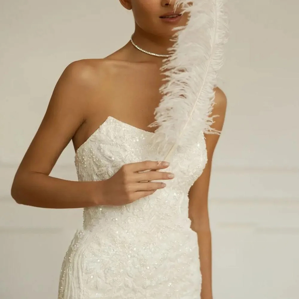 Detailed close-up of a luxury bridal dress bodice emphasizing intricate hand-stitched clear sequins, shimmering beads, and delicate leafy embroidery patterns.
