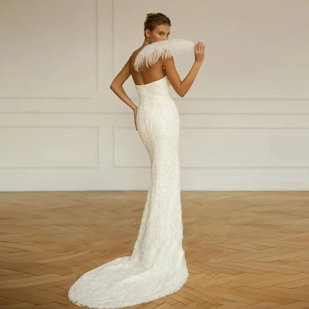 Full rear view of a strapless backless sequin mermaid wedding dress emphasizing a seamless fit, contoured back line, and an elongated lace pool train.