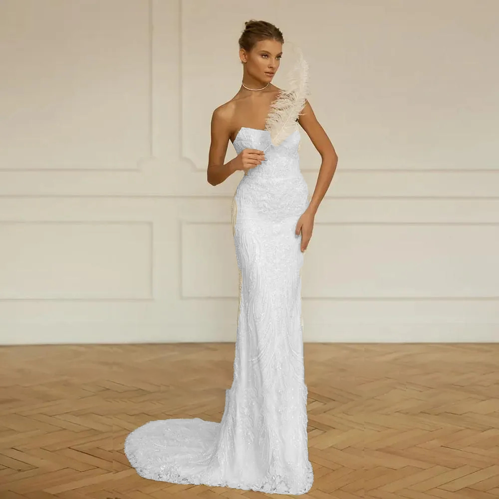 Stately pure white strapless mermaid bridal dress with a heavily beaded bodice, structured hourglass contouring, and a geometric sequined trumpet skirt flare