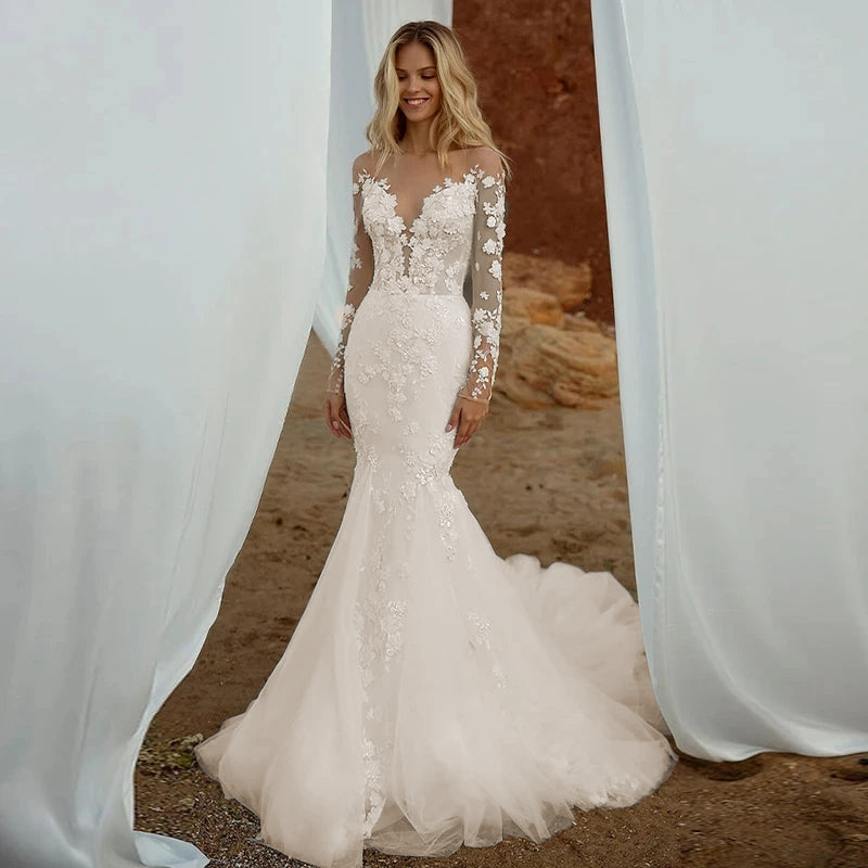 A full-length front view of a boho-style mermaid bridal gown with a deep V-neck and delicate lace detailing on the bodice and sleeves.
