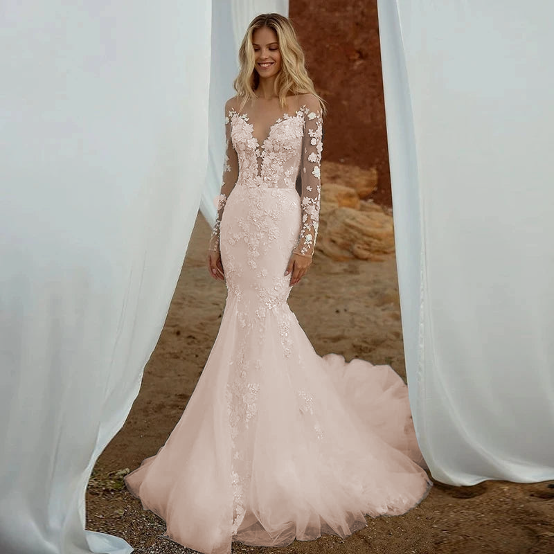 A model showcasing a blush-toned bohemian mermaid wedding dress with a V-neck and detachable train, perfect for a romantic beach wedding.