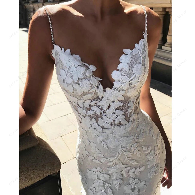 Close-up detail of a bohemian wedding dress bodice, highlighting the intricate floral lace work and delicate beaded spaghetti straps.