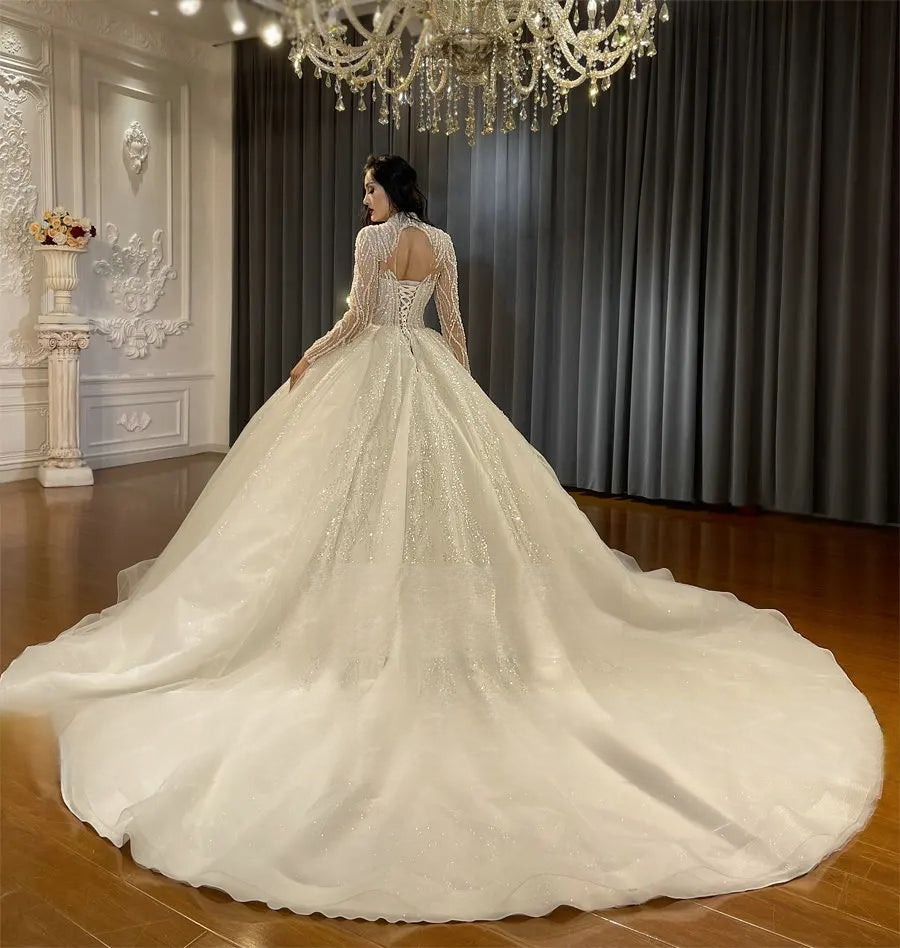 Rear view of a luxury beaded wedding gown showing a sophisticated keyhole back, traditional lace-up corset closure, and a magnificent sweeping shimmering train.