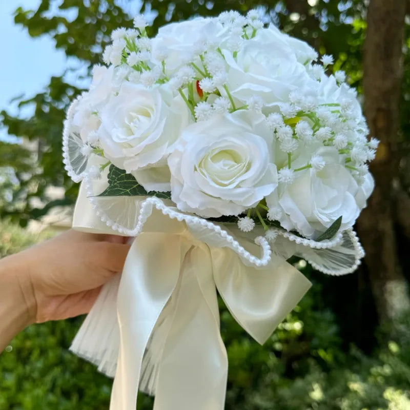 High-angle side view of a white rose wedding bouquet, highlighting the delicate ruffled tulle collar and pearl bead trim.