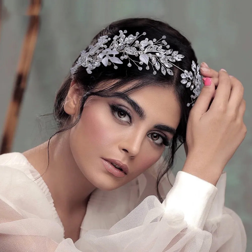 Glamour portrait of a woman leaning her head back, displaying a sparkling rhinestone bridal flower crown nestled into an elegant updo hairstyle.