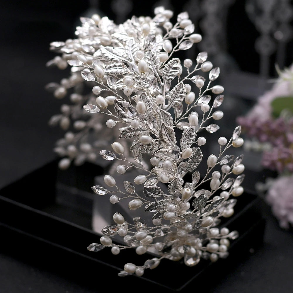 Detailed view of a silver floral tiara crown showing multi-layered silver leaves, white freshwater pearls, and clear marquise rhinestone sprigs.