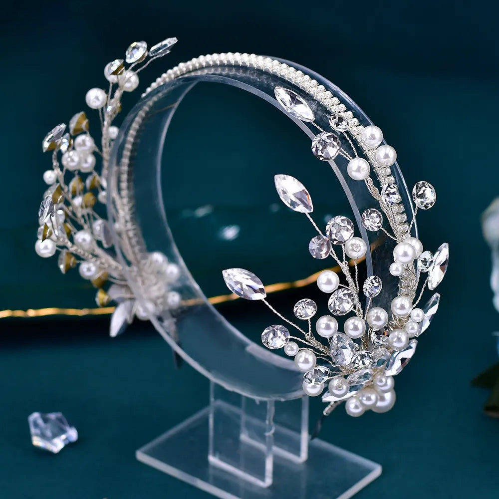 Macro photograph focusing on the fine wirework and crystal-encrusted leaf setting of a luxurious silver glamour tiara bridal headband.