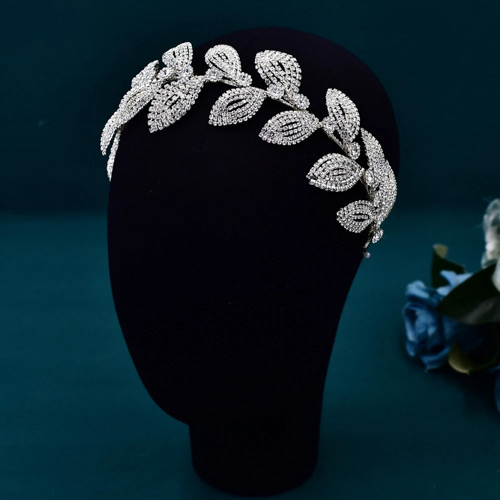 Front view of a glamorous crystal tiara wedding flower crown featuring overlapping pave-set leaf motifs on a black mannequin head.