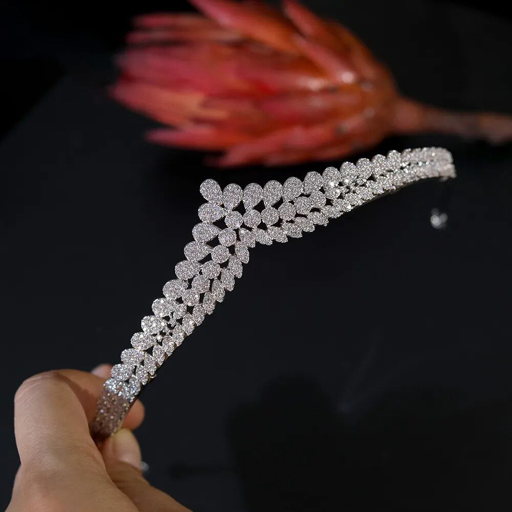 Handheld side-profile view of a delicate silver-plated bridal tiara emphasizing rows of shimmering pave-set round and marquise cz stones.