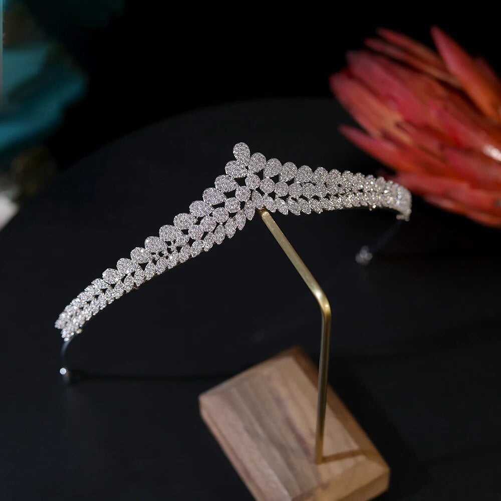 Angled view of a silver-plated cubic zirconia crown headband securely placed on a wooden jewelry display stand.