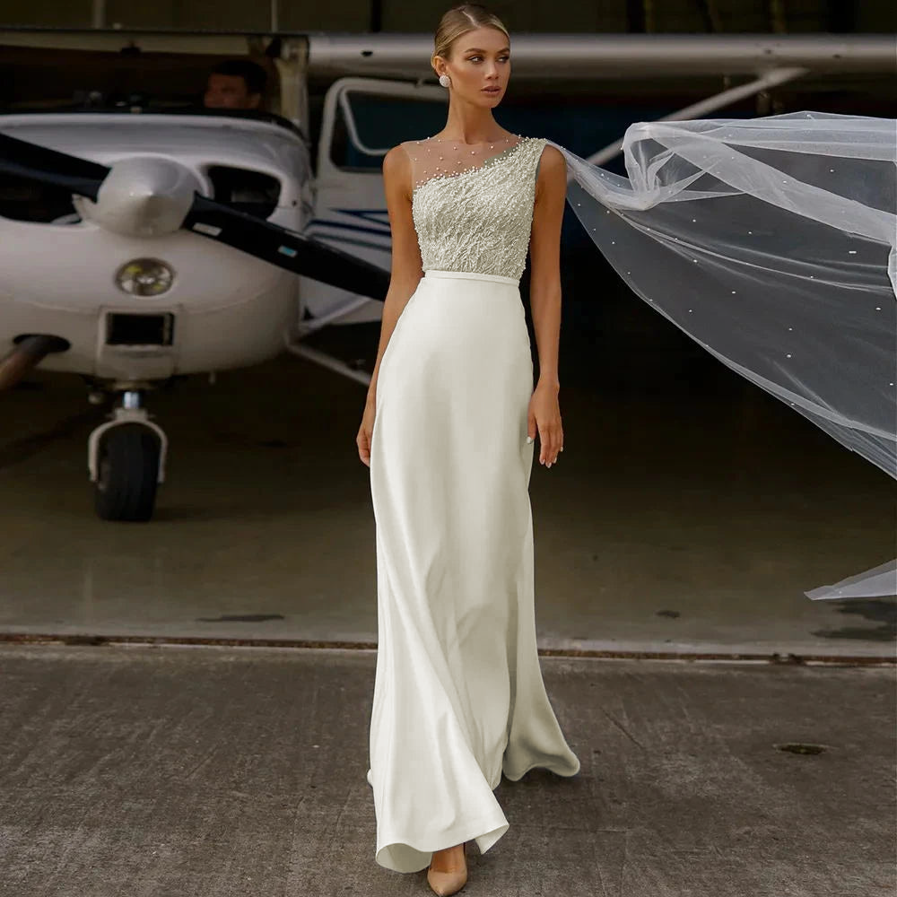 A sophisticated bridal look featuring a beaded bodice with an illusion neckline and a long, flowing chiffon A-line skirt.
