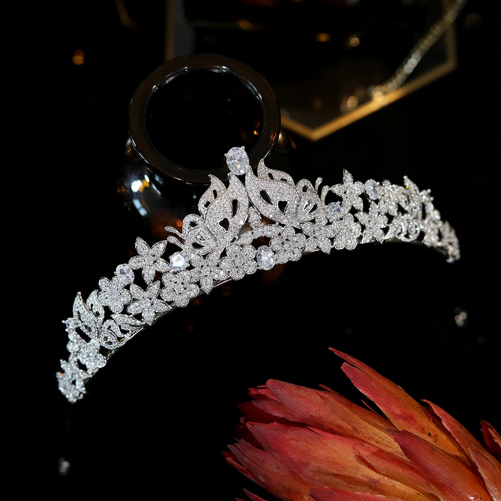 Direct front view of a sparkling rhinestone butterfly wedding tiara balanced on a dark glass display.