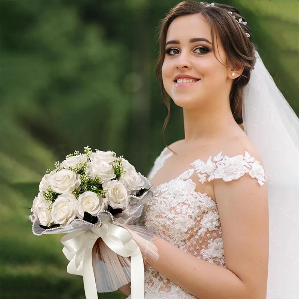 A smiling bride holding an elegant round white artificial bridal bouquet finished with a classic satin ribbon bow.