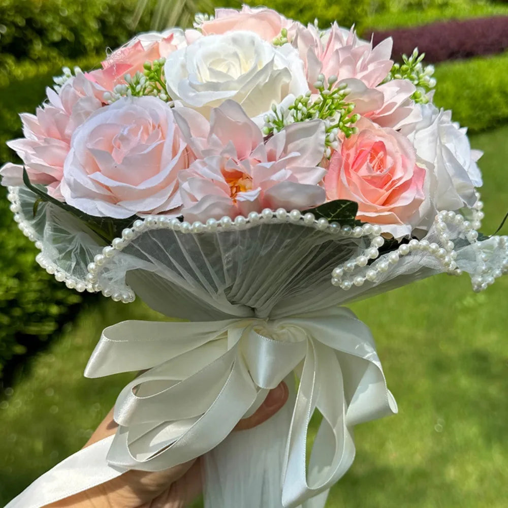 Close-up of a handmade pink and white artificial rose bouquet featuring a sheer tulle collar edged with delicate pearls and a satin bow.