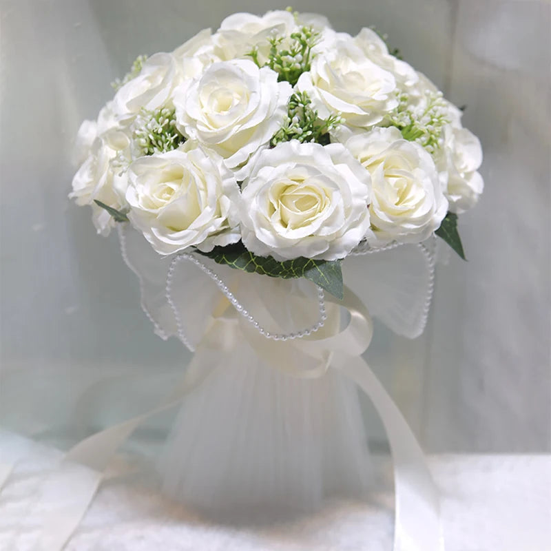 Studio shot of a white faux rose bridal bouquet accented with a pearl-lined sheer mesh bow and flowing satin ribbons.